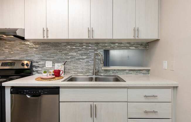 a kitchen with white cabinets and a stainless steel sink
