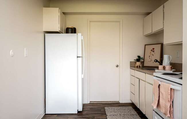A white refrigerator stands in a kitchen with a white door.