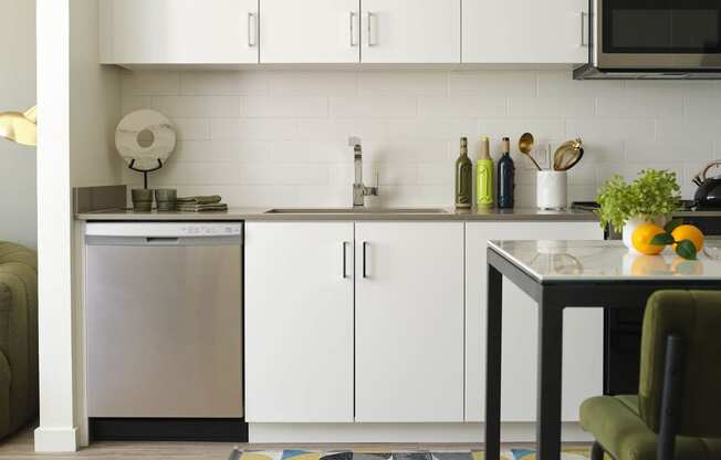 a small kitchen with white cabinets and a table