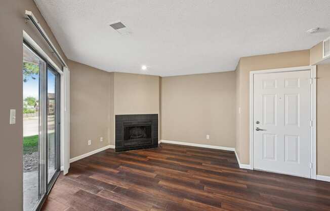 an empty living room with wood floors and a fireplace