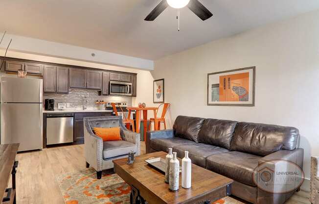 A living room and kitchen with a leather couch and a table.