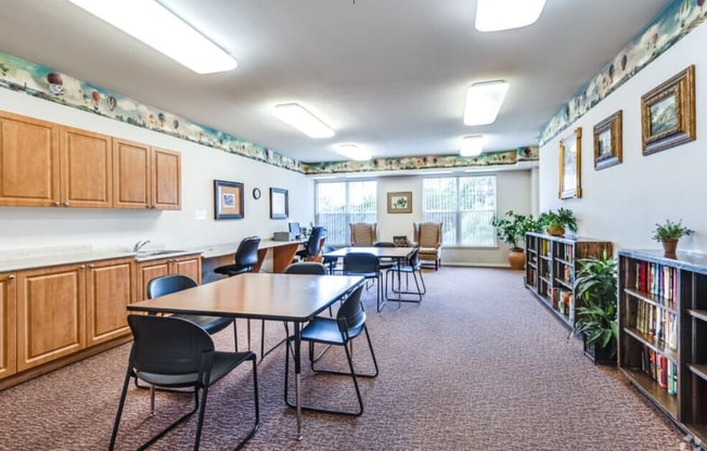 a community room with tables and chairs and a library