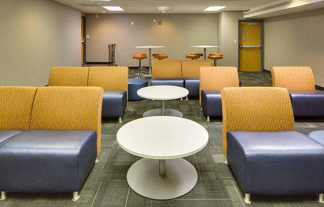 view of several rows of blue and orange chairs with tables between them