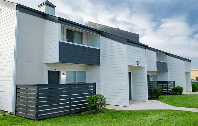 a picture of a white apartment building with a black fence