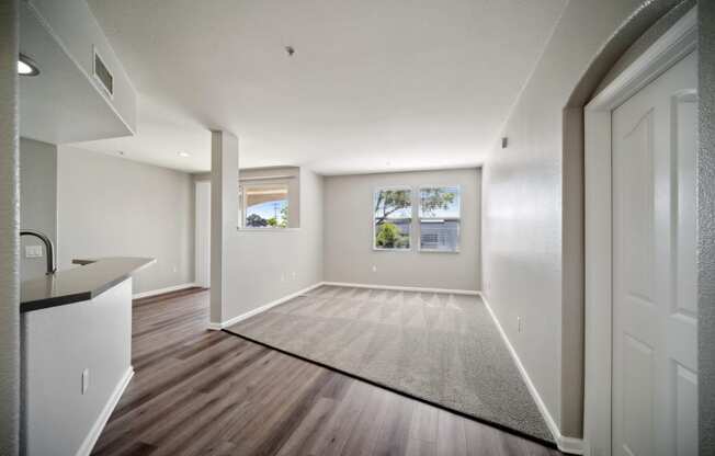 an empty living room and kitchen with white walls and wood floors