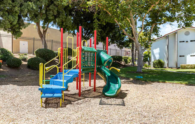 a playground with a green and red slide and a blue and yellow slide