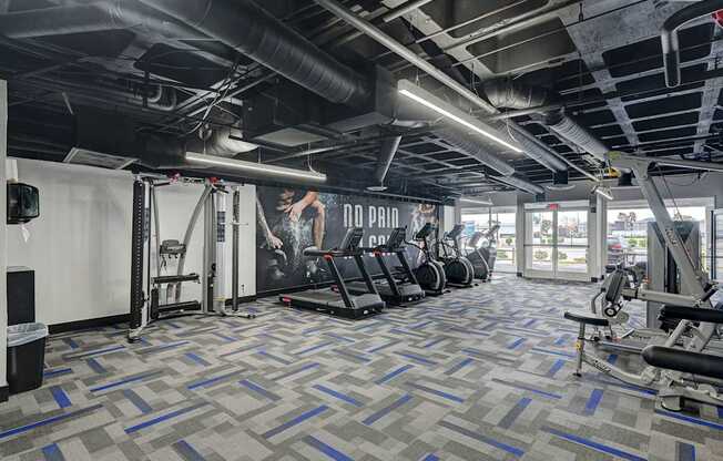 A gym with a variety of equipment including treadmills, weight machines, and a television.