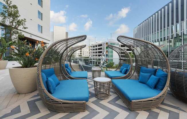 Two blue cushioned chairs and a table are on a patio.