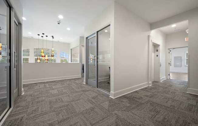 A hallway with a carpeted floor and glass doors.