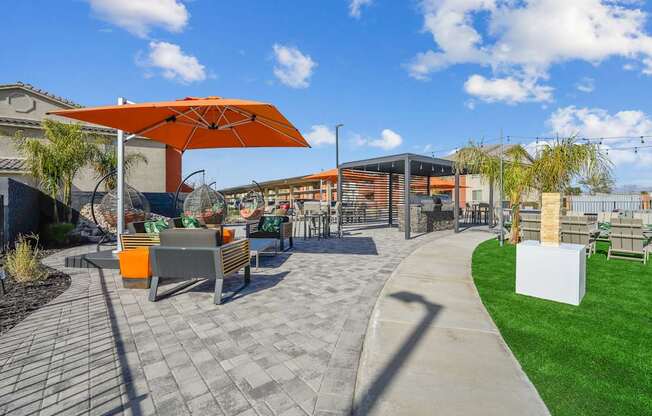 A sunny day at a park with a bench and a shade umbrella.