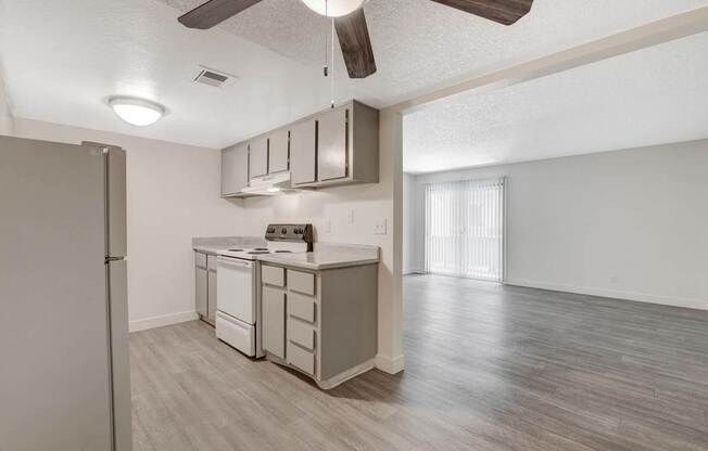 A kitchen with a refrigerator, dishwasher, and a ceiling fan.