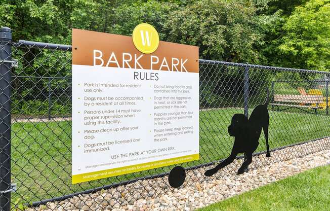 A sign for Bark Park rules is posted on a fence.
