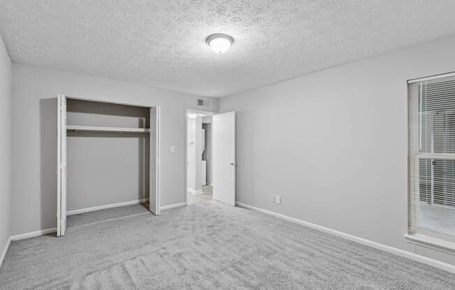 A room with a carpeted floor and a window with blinds.