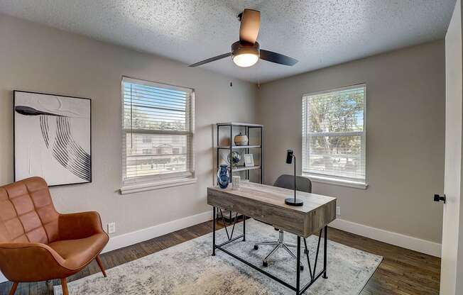 a home office with a desk and a ceiling fan