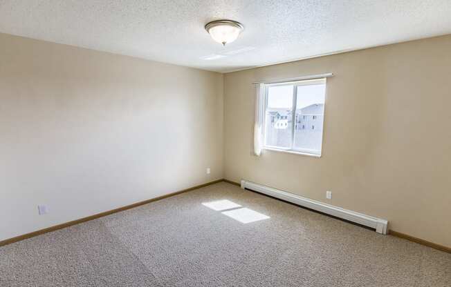 Living room of an empty home with a window at Sunset Ridge Apartments in Bismarck, ND