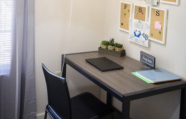 a desk with a laptop and a chair in a room