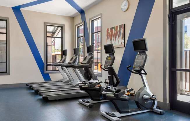 A gym with treadmills and a clock on the wall.