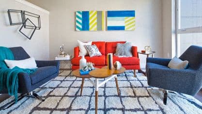 a living room with a red couch and two blue chairs
