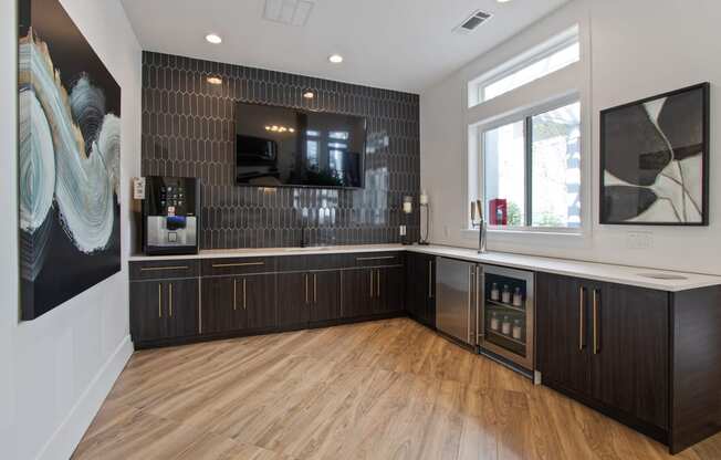 a kitchen with wood floors and black cabinets and a tv