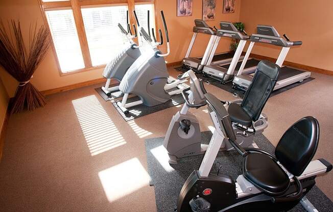 a room with a row of exercise bikes in front of a window