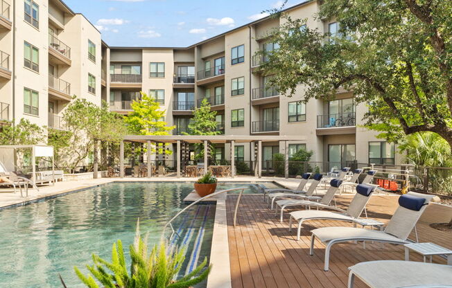 A pool area with chairs and a building in the background.