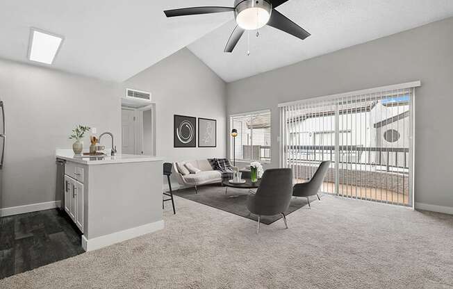 Model Living Room with Carpet and View of Kitchen with Wood-Style Flooring at Crystal Creek Apartments in Phoenix, AZ.