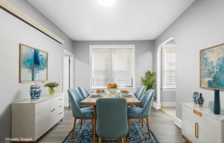 A dining room with a table set for six and a blue rug on the floor.
