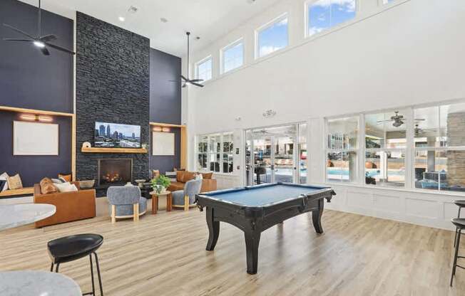 A black pool table is in the middle of a room with a fireplace and a television.