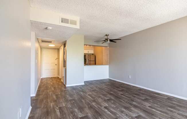 an empty living room with a ceiling fan