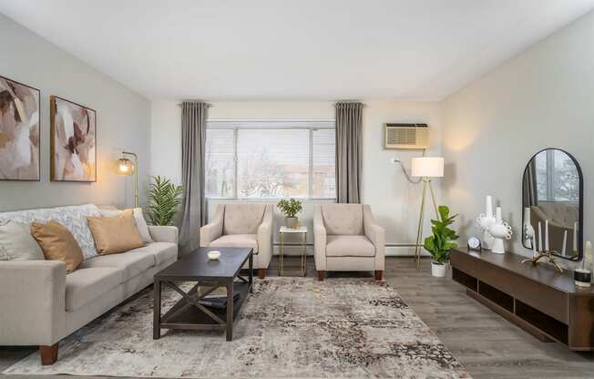 model apartment living room with neutral sofa and chairs and wood media center