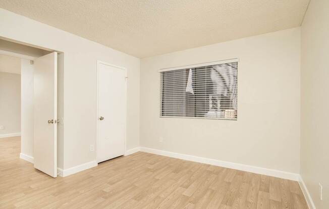 A room with a window and a wooden floor.