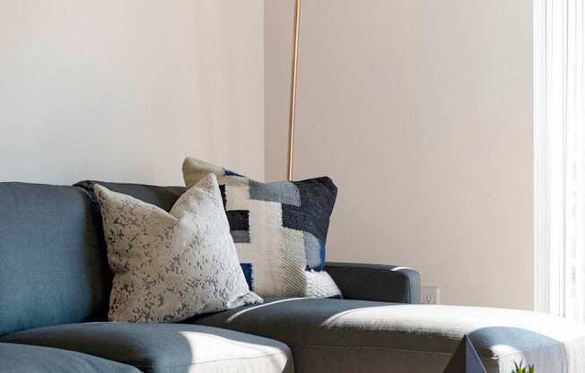 A grey couch with a white lamp above it.