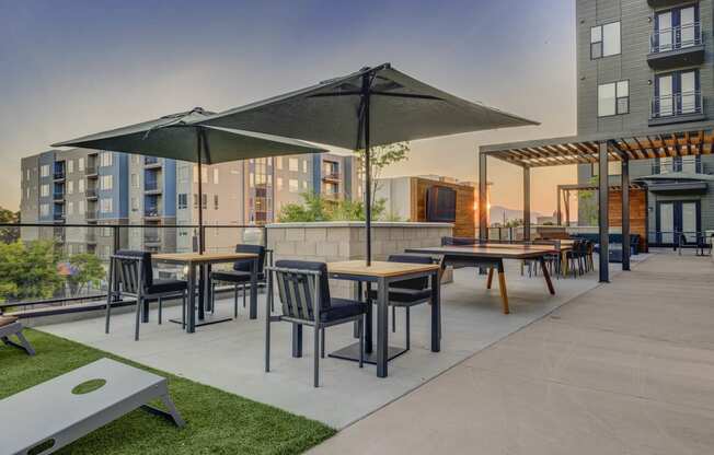 a rendering of an outdoor patio with tables and umbrellas at dusk