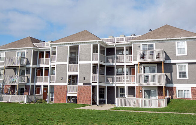 a large apartment building with balconies and a lawn