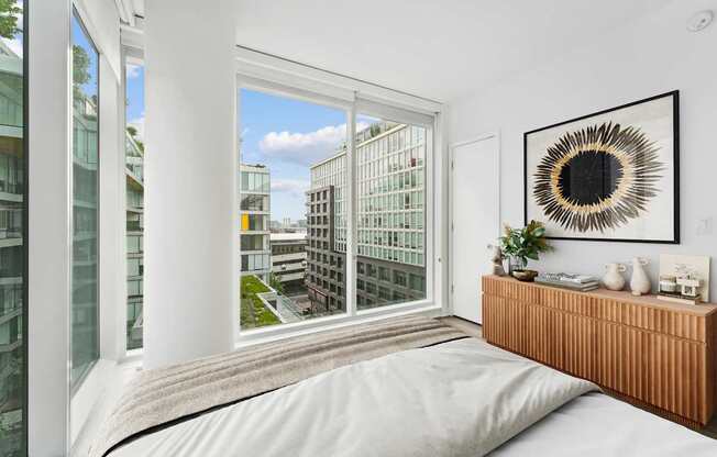 A bedroom with a large window overlooking a cityscape.