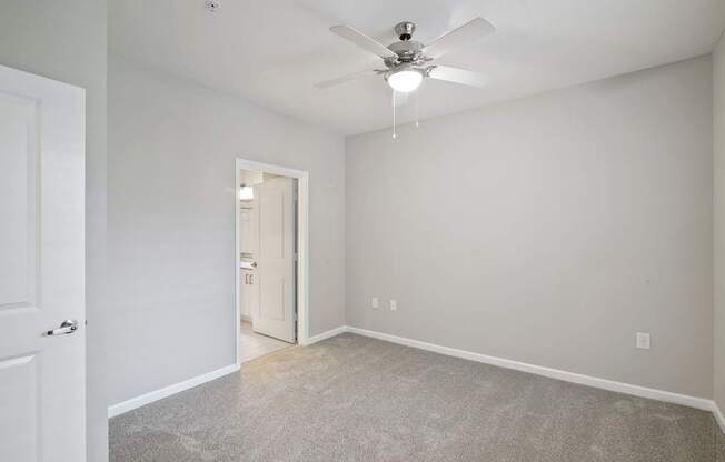 A room with a ceiling fan and carpeted floor.