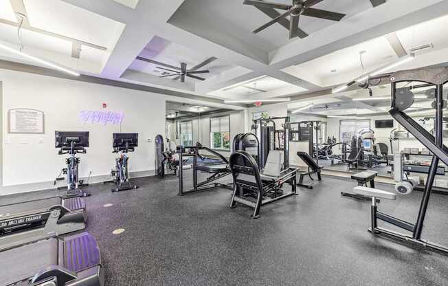 A gym with a variety of equipment including treadmills, weights, and exercise machines.