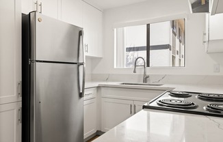 A modern kitchen with a stainless steel refrigerator and a white countertop.