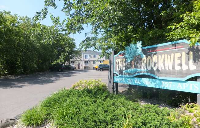 a sign for the rockwell apartments in front of a parking lot