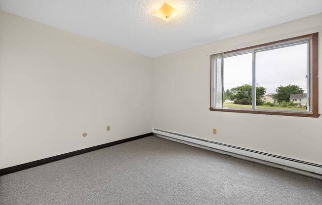 A room with a window and a carpeted floor.