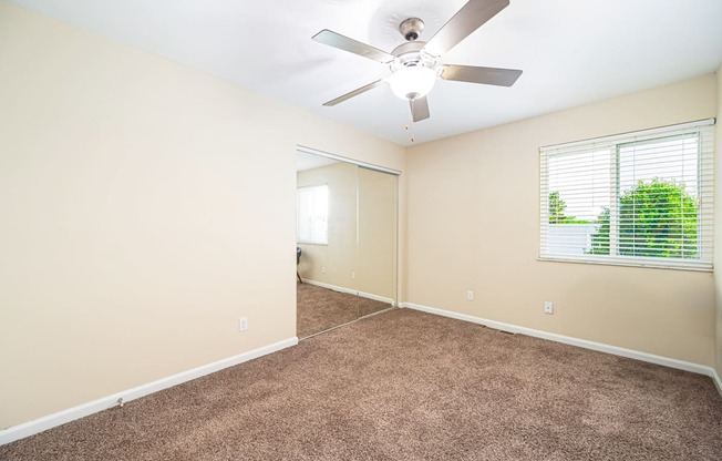 an empty living room with a ceiling fan and a window