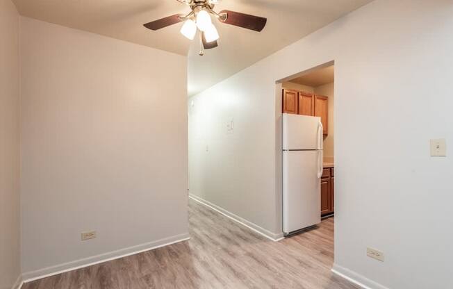 A white refrigerator in a kitchen with a ceiling fan.