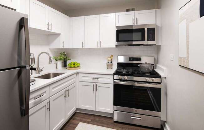 A modern kitchen with white cabinets and stainless steel appliances.
