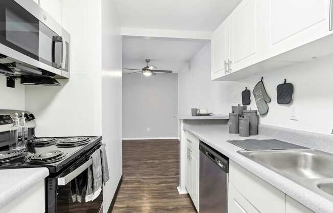 A modern kitchen with white cabinets and a black stove top.