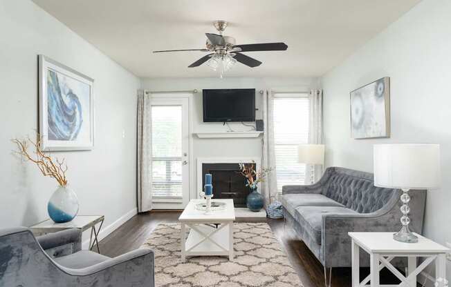 A living room with a grey couch, a white coffee table, and a fireplace.