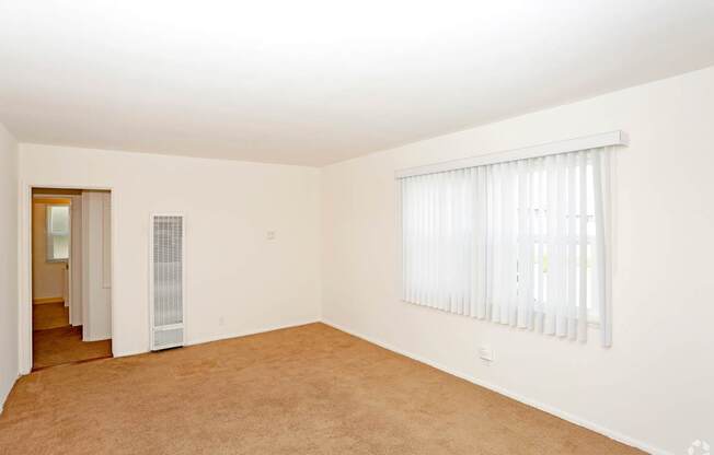 A room with a window covered by white blinds.