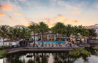 A beautiful view of a pool surrounded by palm trees at sunset.