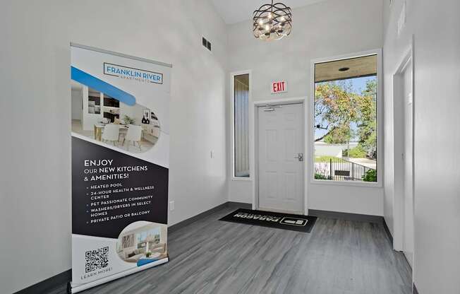 A room with a poster on the wall and a door with an exit sign.