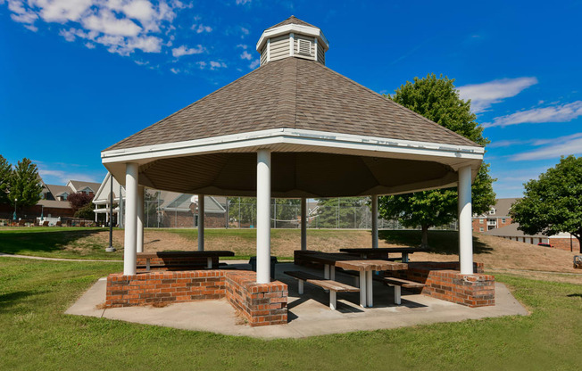 a pavilion with benches and a table in a park
