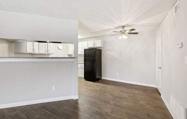 A dining room with a ceiling fan leading into the kitchen at Gwinnett Square Apartments in Duluth, GA